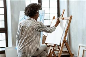 Painter working on a canvas propped on an easel.