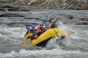 Group in a yellow raft navigating river rapids