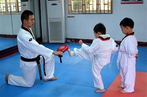Young boy students kicking pad in karate class